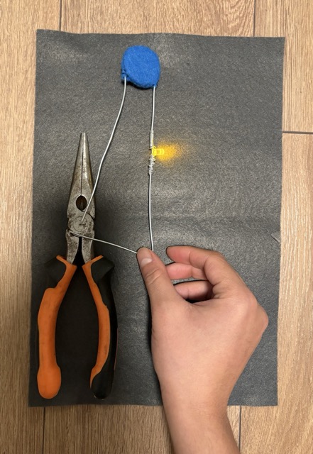 Here the conductor-tester lights up after it touches metal pliers.